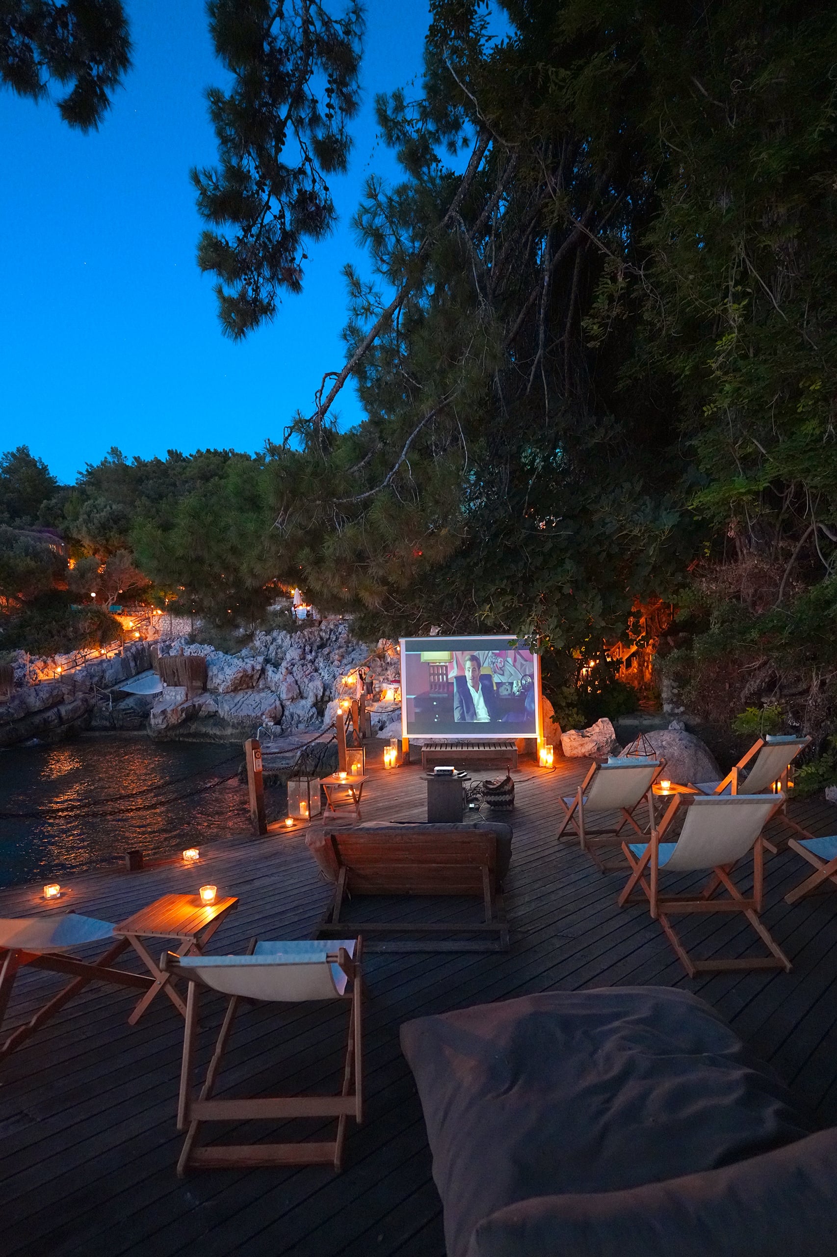 Eine Leinwand im Freien und Sitzplätze im Laternenlicht auf einer Terrasse bei Nacht