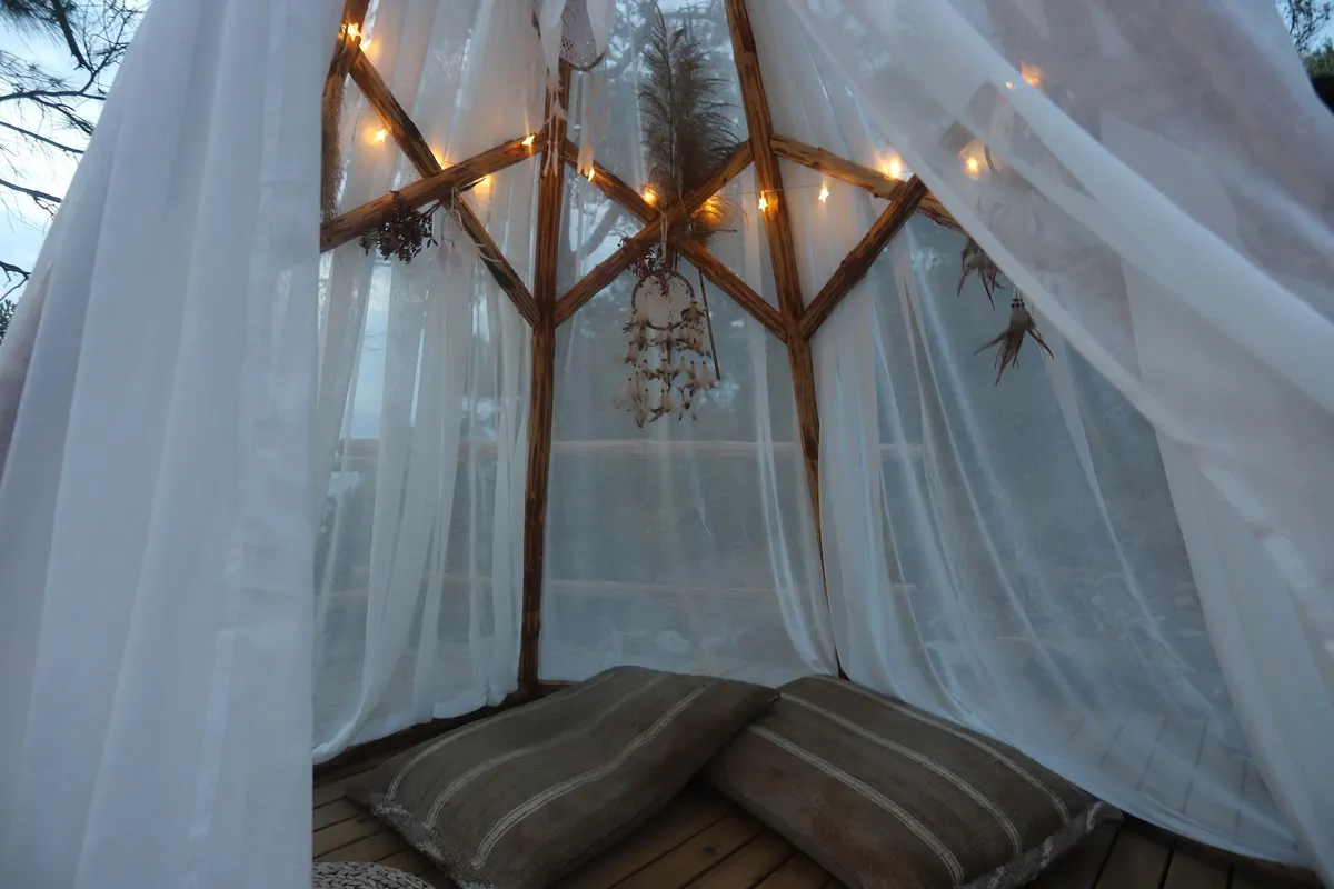 Soft light inside a white tent of sheer curtains.